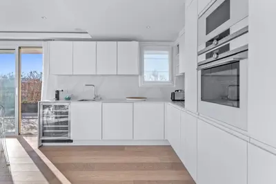 a white kitchen with white cabinets and a window at REF 2033 - Cannes - Sumptuous penthouse with sea view for rent in Cannes