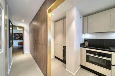 a kitchen with white walls and wooden cabinets at REF 1295 - Cannes Croisette - Sea view apartment for rent in Cannes