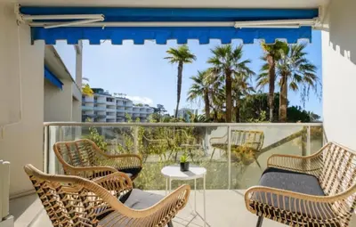 a balcony with chairs and a table and palm trees at Appartement proche du centre de Cannes avec parking in Cannes
