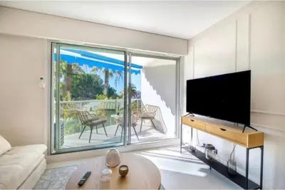 a living room with a tv and a large window at Appartement proche du centre de Cannes avec parking in Cannes