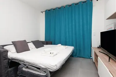 a room with two beds and a tv and a blue curtain at L'AZUERA Cannes center 2P Design 4 Pers Secure Parking in Cannes