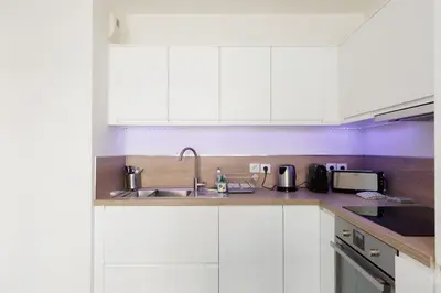 a kitchen with white cabinets and a sink at L'AZUERA Cannes center 2P Design 4 Pers Secure Parking in Cannes