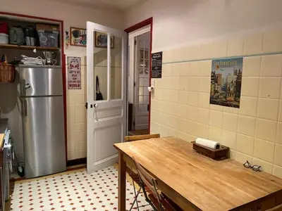 a kitchen with a wooden table and a refrigerator at Trois pièces Gallieni in Cannes