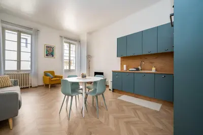 a kitchen with blue cabinets and a table and chairs at Spacious and Bright Near Train Station and Palais des Festivals - BENAKEY in Cannes