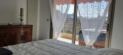 a bedroom with a bed and a large window at Magnifique deux pièces Lacour in Cannes