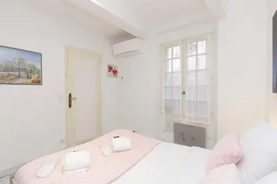 a white bedroom with a bed and a window at Volupte YourHostHelper in Cannes