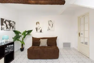 a white living room with a brown ottoman at Volupte YourHostHelper in Cannes
