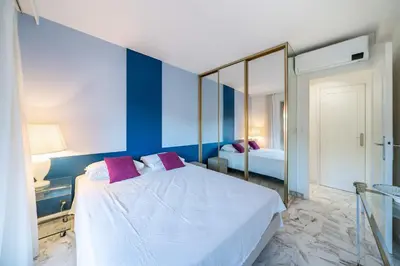 a blue and white bedroom with a bed and a mirror at 2 pièces à deux pas du centre ville de Cannes in Cannes
