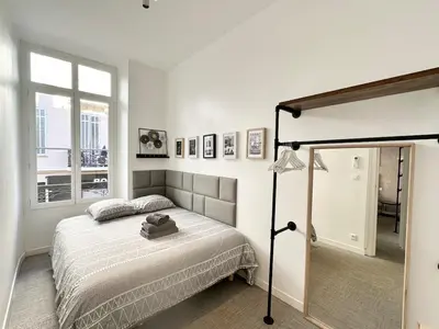 a white bedroom with a bed and a window at 2 bedrooms, large terrace, city center in Cannes