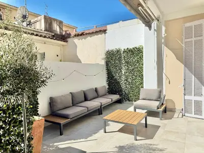 a patio with a couch and two chairs and a table at 2 bedrooms, large terrace, city center in Cannes