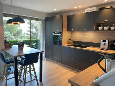 a kitchen with black cabinets and a table with chairs at Blue Dream in Le Cannet