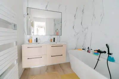 a white bathroom with a tub and a mirror at Blue Dream in Le Cannet
