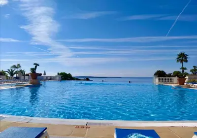 a large swimming pool with the ocean in the background at Les Ingres 2 - SCLS Rentals in Cannes