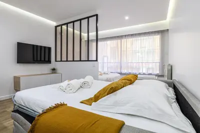 two beds in a bedroom with a tv on the wall at 8 MERLE T2 - Appartement moderner pour 4 personnes proche Palais in Cannes