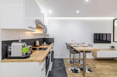a kitchen with white cabinets and a wooden counter top at 8 MERLE T2 - Appartement moderner pour 4 personnes proche Palais in Cannes