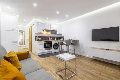 a living room with a couch and a kitchen with a tv at 8 MERLE T2 - Appartement moderner pour 4 personnes proche Palais in Cannes