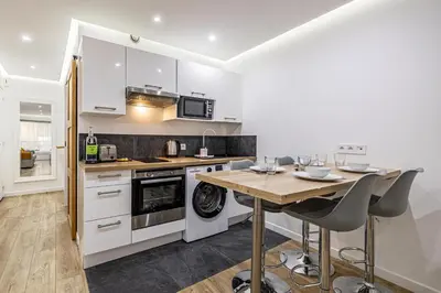 a kitchen with white cabinets and a wooden table at 8 MERLE T2 - Appartement moderner pour 4 personnes proche Palais in Cannes