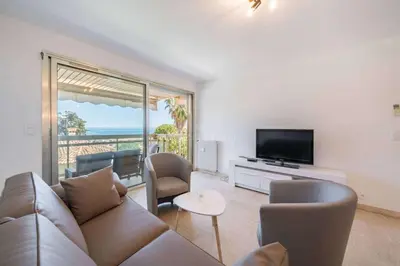 a living room with a couch and a television at Appartement Vue Mer au Palm Beach in Cannes