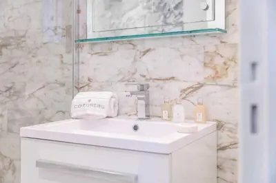 a white bathroom with a sink and a mirror at Appartement Vue Mer au Palm Beach in Cannes