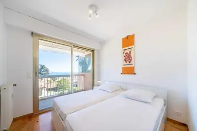 a bedroom with a bed and a large window at Appartement Vue Mer au Palm Beach in Cannes