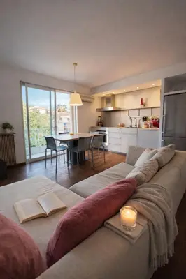 a living room with a couch with a table and a kitchen at VERCORS next to the Sea & Beach in Cannes