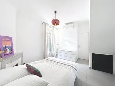 a white bedroom with a bed and a tv at Maison Noble in Cannes