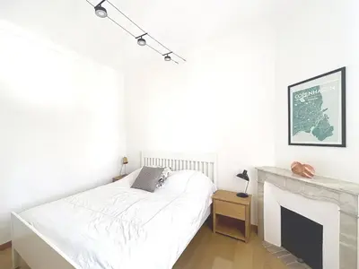 a white bedroom with a bed and a fireplace at Maison Noble in Cannes