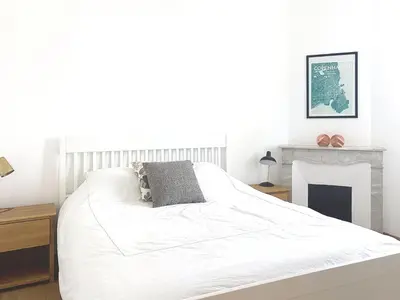 a white bedroom with a bed and a fireplace at Maison Noble in Cannes
