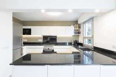 a kitchen with white cabinets and a black counter top at Ground-Floor 2 Br - Near Centre & Beaches in Cannes