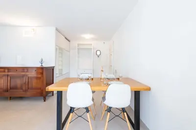 a dining room with a wooden table and white chairs at Ground-Floor 2 Br - Near Centre & Beaches in Cannes