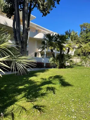 a building with palm trees in front of a yard at Appartement au centre de Cannes à deux pas du festival in Cannes