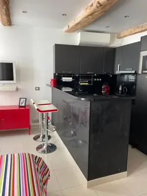 a kitchen with black cabinets and a red stool at Magnifique studio proche palais des festivals in Cannes