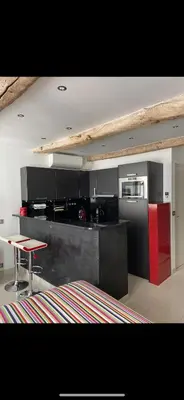 a kitchen with black and red cabinets and a table at Magnifique studio proche palais des festivals in Cannes