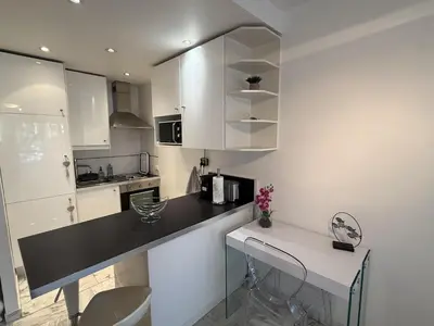 a kitchen with a black counter and white cabinets at Central Studio in Cannes Near The Martinez - 2351 in Cannes