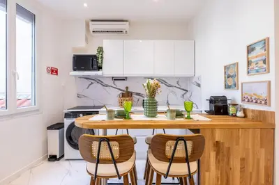 a kitchen with a wooden table and chairs at Esprit Bohème - Elegant & central près du Palais in Cannes