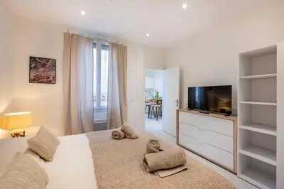 a bedroom with a large bed with a tv and a room at Esprit Bohème - Elegant & central près du Palais in Cannes