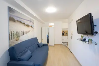a living room with a blue couch and a flat screen tv at Studio near Palais des Festivals in Cannes