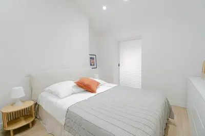 a white bedroom with a bed with an orange pillow at La Mouette-appartement au Vieux Port in Cannes