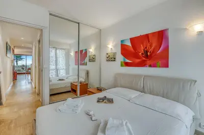 a bedroom with a white bed and a large mirror at Cannes Sea View - Port du Moure Rouge - Happy Rentals in Cannes