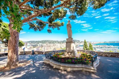 a statue in a flower garden with a view of a city at Cannes Sea View - Port du Moure Rouge - Happy Rentals in Cannes