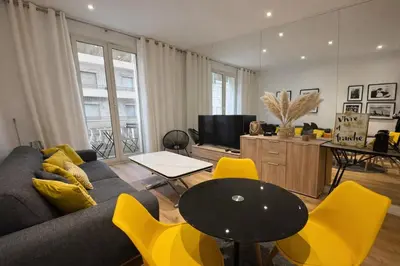 a living room with a couch and a table and yellow chairs at 2 pièces - Croisette in Cannes