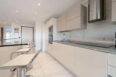 a kitchen with white cabinets and tables and chairs at 1-Br Apartment with Terrace Near City Centre in Cannes