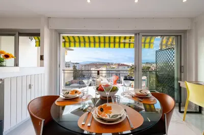 a dining room with a glass table and a balcony at 1-Br Apartment with Terrace Near City Centre in Cannes