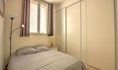 a bedroom with a bed with a window and a lamp at Lovely 1BR flat 15 min walk from La Croisette in Cannes