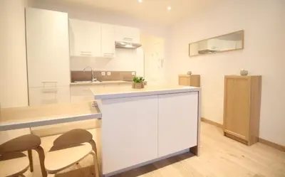 a white kitchen with two chairs and a counter at Lovely 1BR flat 15 min walk from La Croisette in Cannes
