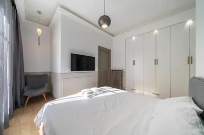 a white bedroom with a bed and a tv at COZYSTAY - 1124 - 3-Bedroom Apartment in the Heart of Cannes with Terrace in Cannes