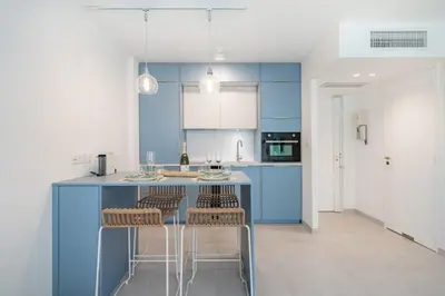 a kitchen with blue cabinets and bar stools at Chic appartement 2 pièces in Cannes