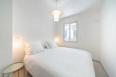 a white bedroom with a bed and a window at Chic appartement 2 pièces in Cannes