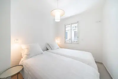 a white bedroom with two beds and a window at Chic appartement 2 pièces in Cannes