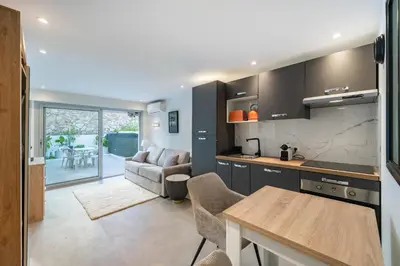 a kitchen and living room with a couch and a table at Charming bright studio with spacious outdoor area in Cannes
